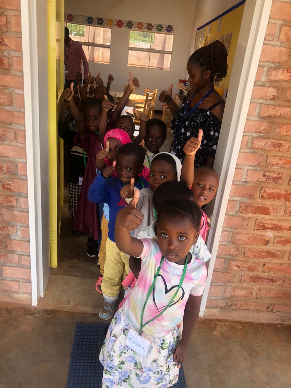 Children line up to enter their classroom giving a thumbs up