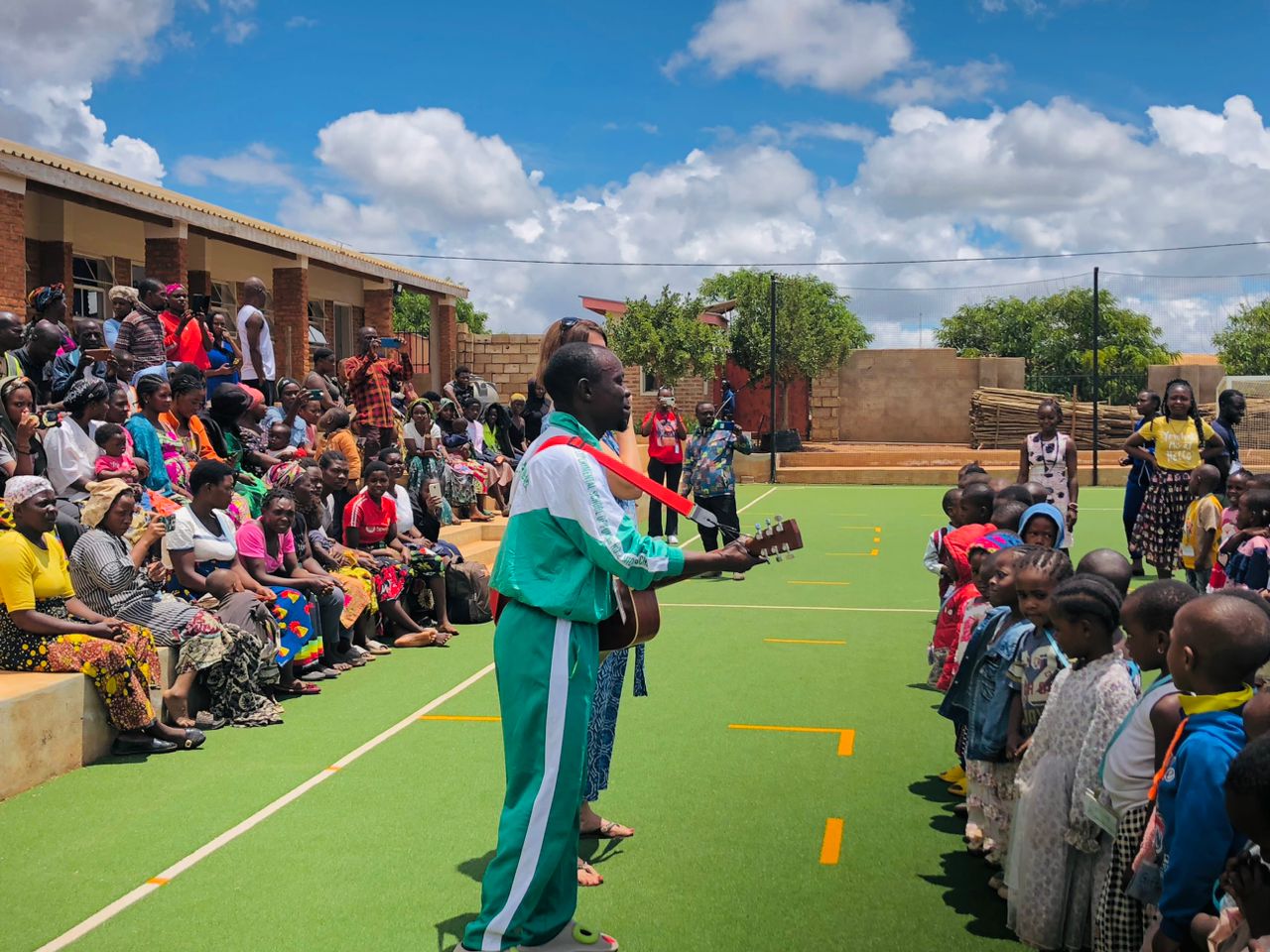 A musician plays guitar as children and parents gather